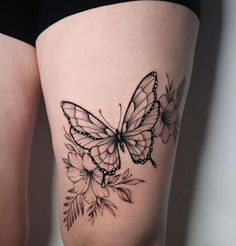 a woman's thigh with a butterfly and flowers tattoo on the side of her leg