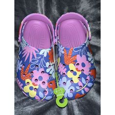 Add A Touch Of Feminine Charm To Your Little Girl's Footwear Collection With These Crocs Classic Printed Floral Clogs In Purple And Pink. These Sandals Are Perfect For Any Occasion, Whether It's A Day Out With The Girls Or A Family Gathering. The Crocs Classic Design Ensures Comfort And Durability, While The Floral Pattern Adds A Cute And Stylish Touch. Available In Us Shoe Size 2, These Clogs Are Perfect For Girls Who Love To Play And Explore. Get Your Hands On These Crocs Classic Printed Flora Cute Non-slip Clogs For Spring, Cute Non-slip Spring Clogs, Fun Spring Clogs, Cute Summer Clogs For Playtime, Cute Summer Playtime Clogs, Spring Multicolor Non-slip Clogs, Casual Purple Clogs For Summer, Fun Multicolor Clogs For Spring, Playful Multicolor Clogs With Round Toe