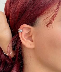 a woman with red hair is wearing an ear cuff and has a ring on her left ear