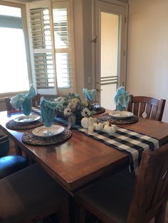 a dining room table with plates and flowers on it