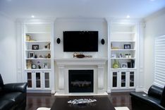 a living room with black leather chairs and a flat screen tv mounted on the wall