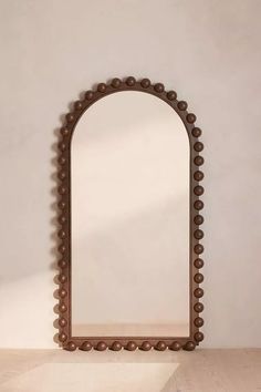 a mirror sitting on top of a wooden table next to a white wall and floor