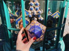 a hand is holding an item in front of a glass display case with blue and gold decorations