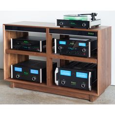 an old record player and other electronic equipment on a wooden shelf in front of a white wall