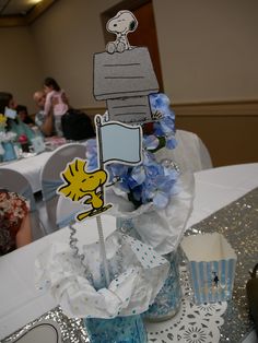 a table topped with a vase filled with blue flowers and cupcakes on top of it