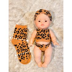 a baby doll is laying next to a pair of leopard print diapers and socks