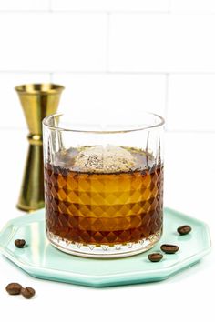 a glass filled with coffee sitting on top of a blue plate