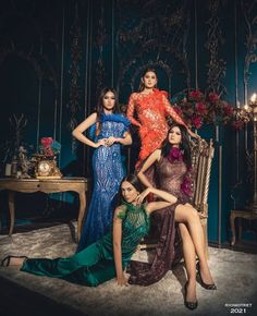 four women in evening dresses posing for a photo with one woman sitting on a chair