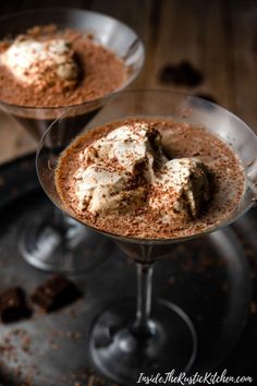 two glasses filled with dessert sitting on top of a metal tray next to each other