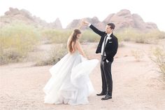 a bride and groom dancing in the desert