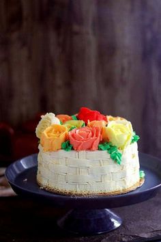 a cake with flowers on top is sitting on a blue platter and sits on a wooden table