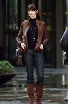 the devil wears prada style she is wearing brown boots and a black shirt with her hands in her pockets