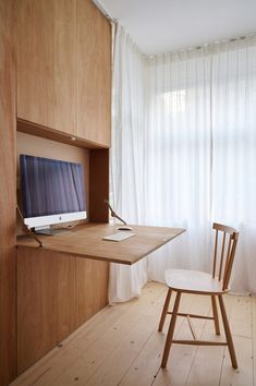 a wooden desk with a computer monitor on top of it next to a white chair