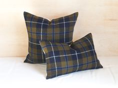 two plaid pillows sitting on top of a bed