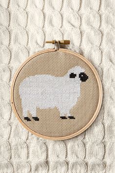 a cross stitch sheep with black eyes on it's face