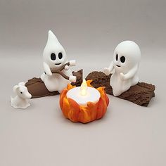 there are three small white figures sitting around a lit candle in the shape of a flame