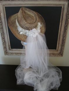 a hat is sitting on top of a table next to a framed photo and veil