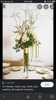 a vase filled with white flowers sitting on top of a wooden table next to plates