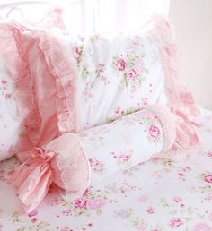 a bed with pink flowers and ruffles on the pillowcase, along with two pillows