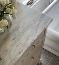 a vase with white flowers sitting on top of a marble counter