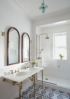 a bathroom with two sinks and three mirrors on the wall next to a bathtub