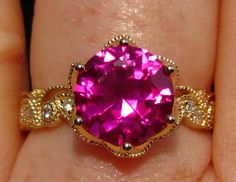 This IVY engagement ring features a lab pink sapphire and floral yellow gold filigree that looks like sparkly lace on your finger! The center stone is a 9mm lab-grown hot pink sapphire. It has a glowing bright pink color, nice cut and flawless clarity. The lab-grown sapphire has all the properties of natural sapphire. The sapphire is set in a Lily filigree head that supports it with a fluid floral design. The band features delicate floral filigree and diamonds, that look like sparkly lace on you Pink Intricate Design Jewelry For Anniversary, Pink Jewelry With Intricate Design For Anniversary, Gold Pink Sapphire Jewelry With Center Stone, Elegant Pink Ruby Ring With Diamond Cut, Pink Diamond Cut Ruby Ring Gift, Pink Diamond Cut Ruby Ring For Wedding, Pink Rings With Intricate Design For Anniversary, Formal Pink Rings With Intricate Design, Wedding Pink Ruby Ring With Diamond Cut