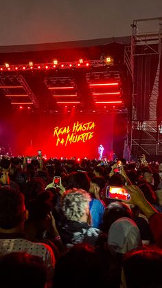 a large group of people standing on top of a stage with red lights in the background