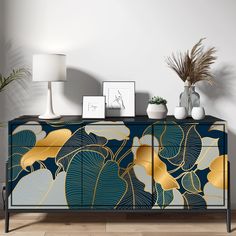 a sideboard with gold leaves painted on it and two vases sitting on top