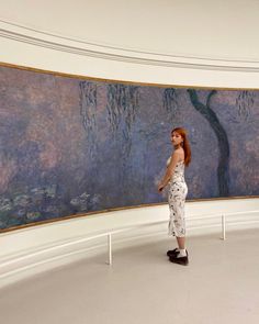 a woman standing in front of a large painting