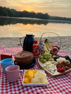 a picnic table with food and drinks on it next to the water's edge