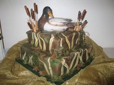 a duck is sitting on top of a camouflage cake with sticks sticking out of it