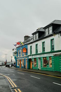 an empty street with shops on both sides and cars parked along the road in front