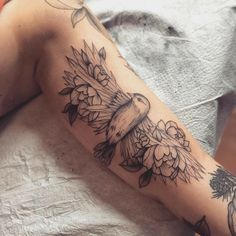 a woman's arm with flowers and a bird tattoo on the left side of her arm