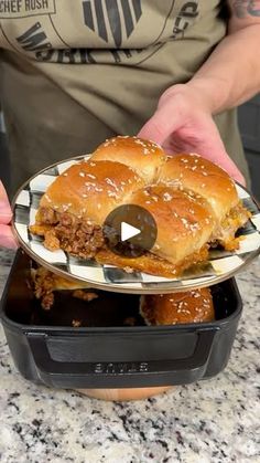 a person holding a plate with a large sandwich in it on top of a counter