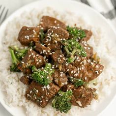 a white plate topped with meat and broccoli covered in sesame seed flakes