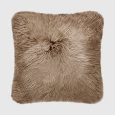 a beige pillow with long fur on the front and back, it has a square shape