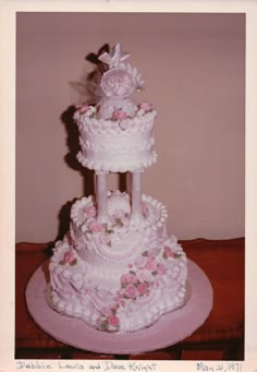 a three tiered wedding cake with pink flowers on the bottom and white icing