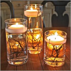 three glass vases filled with candles on top of a wooden table