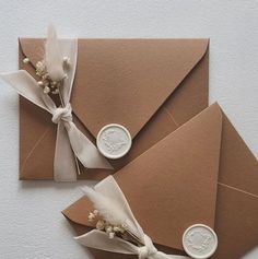 two brown envelopes with white ribbon and wax stamp on them, tied to each other