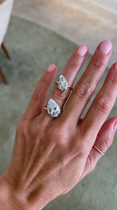 a woman's hand with two engagement rings on her left and the middle finger