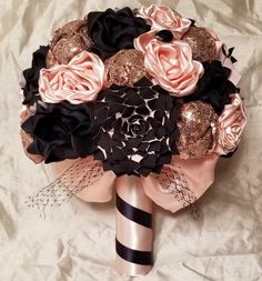 a bridal bouquet with black, pink and gold flowers on white fabric background for decoration