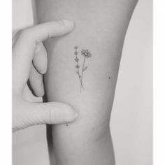 a woman's arm with a small flower tattoo on the left side of her arm