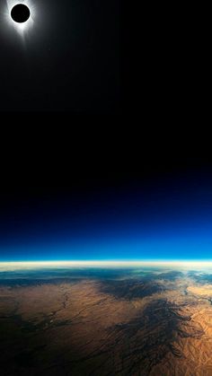 the solar eclipse seen from space with earth's horizon in the foreground and distant land