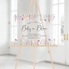 a baby in bloom welcome sign on a wooden easel