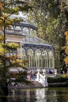 people are sitting on the steps in front of a building with a glass roof that is surrounded by trees and water