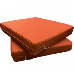 two orange cushions sitting side by side on top of each other, one is folded and the other has a zippered closure