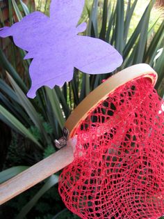 there is a purple fish on top of a red net in front of some plants