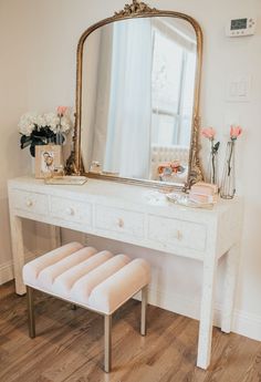 a white vanity with a mirror and stool