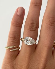 a woman's hand with three different rings on it and an oval shaped diamond in the middle