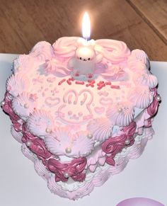 a heart shaped cake with a lit candle on top